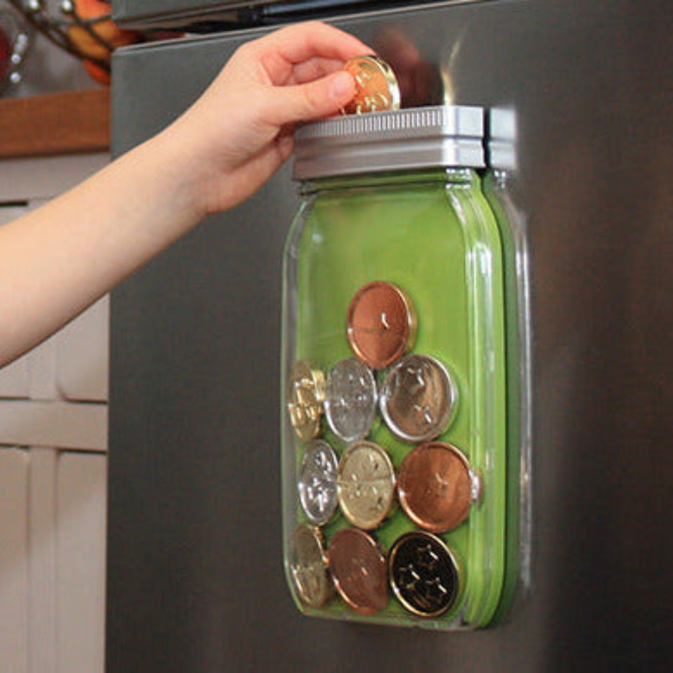 Green magnetic reward jar, displayed on a fridge and being used by a child